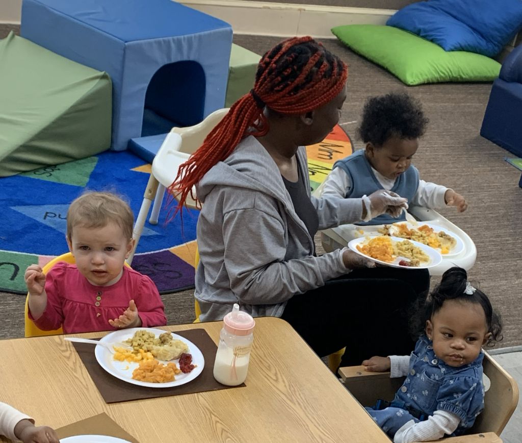 Toddlers enjoying mealtime with teacher